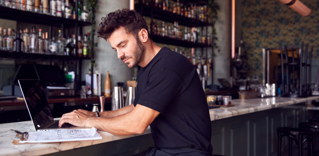Restaurant Bar Owner Sitting At Counter Working On Laptop